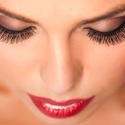 A woman with red lipstick and long lashes.